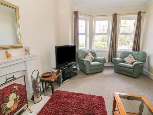 a living room with two chairs and a flat screen tv at Minffordd in Newborough