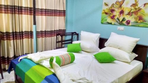 a bedroom with a bed with green and white pillows at Santosa Villa in Galle
