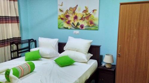 a bedroom with a bed with green and white pillows at Santosa Villa in Galle