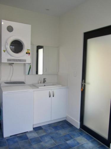 a white kitchen with a sink and a microwave at Storm Bay Cottage in Augusta