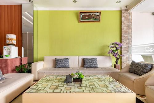 a living room with a couch and a green wall at RedDoorz Syariah @ Soekarno Hatta Indah 2 in Blimbing