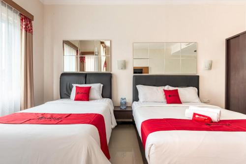 two beds in a room with red pillows at RedDoorz Syariah @ Soekarno Hatta Indah 2 in Blimbing