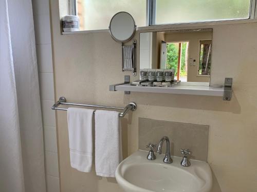 a bathroom with a sink and a mirror and towels at Tin Can Bay Motel in Tin Can Bay
