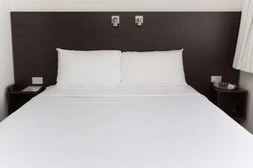 a large bed with white pillows and two night stands at St Ives Apartments in Hobart