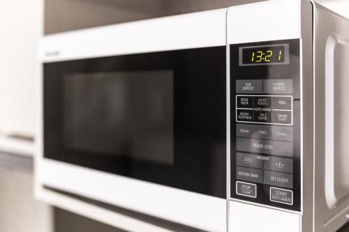 a microwave oven with a digital clock on it at St Ives Apartments in Hobart