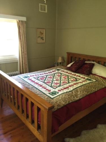 a bedroom with a bed with a quilt on it at Akarana Cottage in Leura