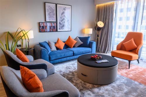 a living room with blue couches and orange chairs at Oakwood Residence Sukhumvit Thonglor Bangkok in Bangkok