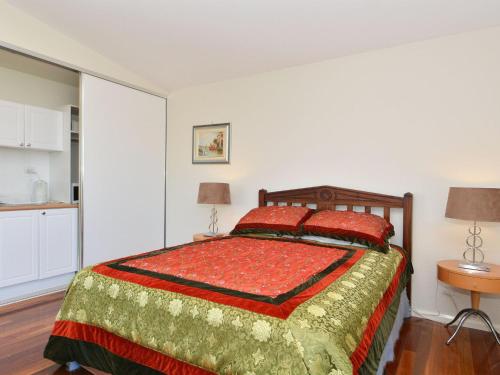 a bedroom with a bed with a red and green blanket at Morisset Waterview 1bdr Studio in Morisset East