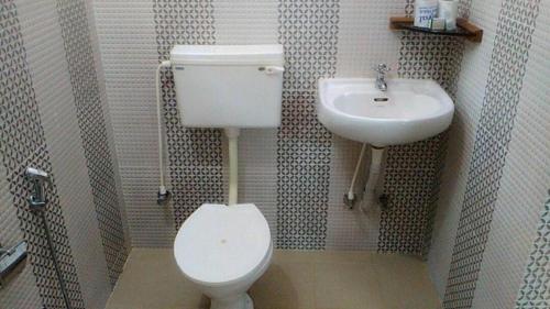 a bathroom with a toilet and a sink at Jickys Nest in Varkala