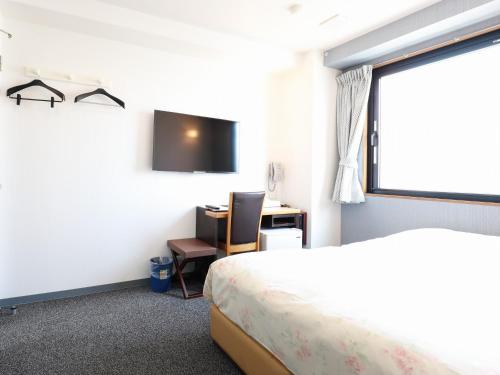 a bedroom with a bed and a desk and a tv at Hiroshima Town Hotel in Hiroshima