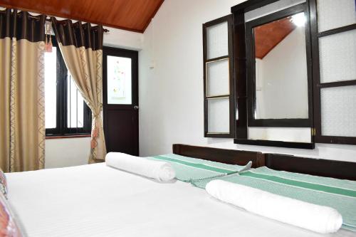 a bedroom with a bed with white sheets and windows at Arachiwil Green Nature Resort in Puttalam