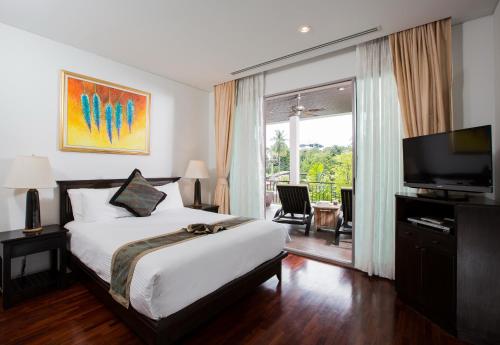 a bedroom with a bed and a television and a balcony at Kata gardens 2 bedroom near Kata beach 3B in Kata Beach