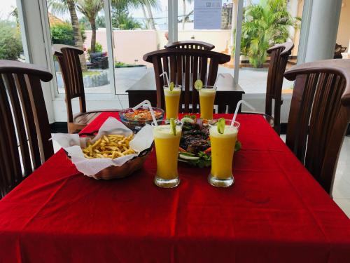 a red table with a plate of food and drinks at Bochum Lanka Resort in Beruwala
