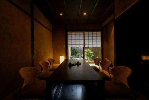 a dining room with a table and chairs and a window at Rinn Premium Machiya Kunpu in Kyoto