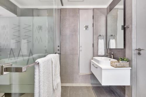 uma casa de banho branca com um lavatório e um chuveiro em Sandton Apartment 15 West Road South em Joanesburgo