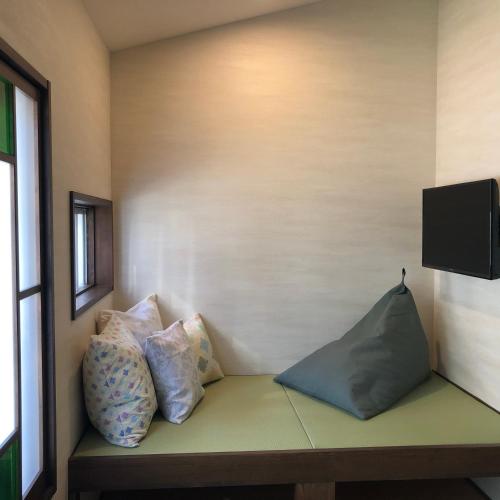 a room with pillows on a bench with a tv at Imakumano Terrace - Mokubei An 木米庵 in Kyoto