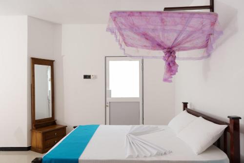 a bedroom with a bed and a mirror and a window at Kandyan White Holiday Homes in Kandy