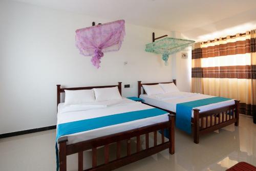 two beds in a room with umbrellas on the wall at Kandyan White Holiday Homes in Kandy