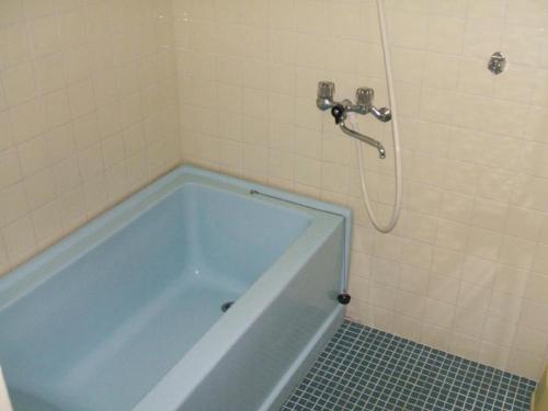ein Badezimmer mit einer blauen Badewanne und einer Dusche in der Unterkunft Weekly Harbourview Mansion Main Building / Vacation STAY 74562 in Naha