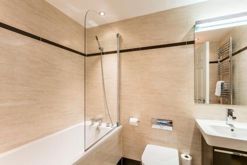 a bathroom with a tub and a sink and a shower at Golf Apartment @ Carus Green in Kendal