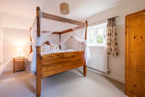 a bedroom with a wooden bed with a canopy at 1 Roseanna Cottage, Middleton - Aldeburgh Coastal Cottages in Middleton