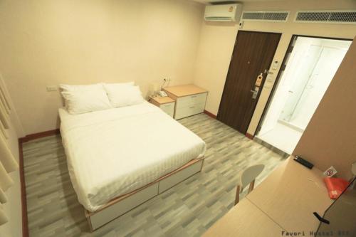a small room with a bed and a table and a door at Favori Hostel Bangkok Surawong in Bangkok
