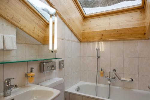 a bathroom with a sink and a toilet and a window at Hotel Holiday in Zermatt