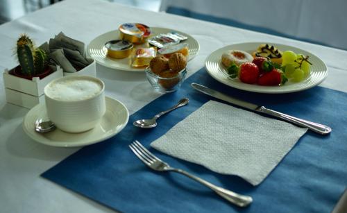 a table with plates of food and a cup of coffee at Hotel Marina in Marina di Massa