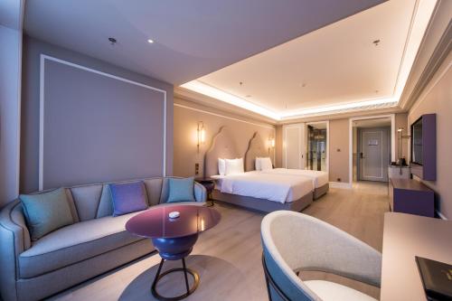 a hotel room with a bed and a couch at Mercure Hotel Changchun Hengxing in Changchun