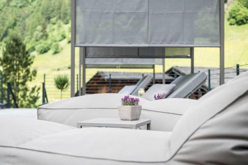 a row of white couches with a plant on a table at Hotel Jaufentalerhof in Racines