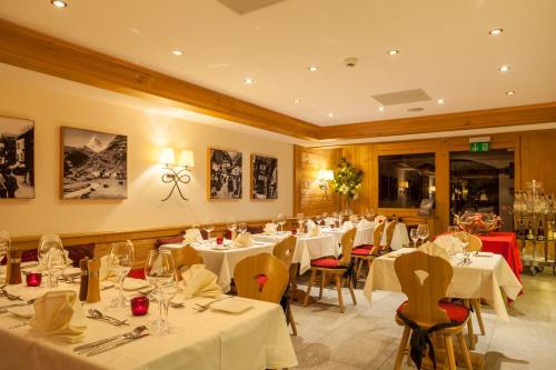 uma sala de jantar com mesas e cadeiras brancas em Hotel Holiday em Zermatt