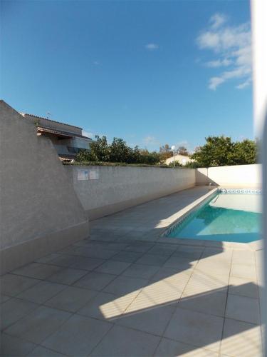 - une piscine à côté d'un mur en béton dans l'établissement LES AMANDINES, au Cap d'Agde
