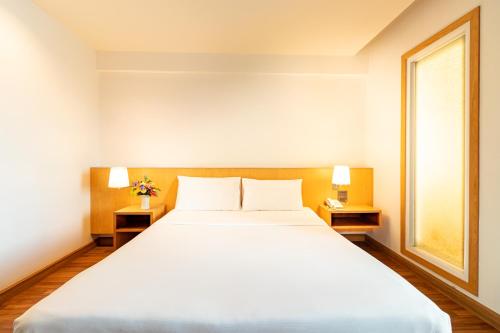 a bedroom with a large white bed and a window at Viva Hotel Songkhla in Songkhla