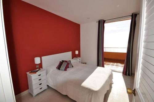 a bedroom with a white bed and a red wall at DUPLEX DE CARA EL MAR 210 m2 in Tamariu