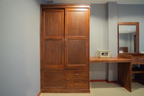 a wooden cabinet next to a desk with a clock at Little Paradise Haad Rin Koh Phangan in Haad Rin