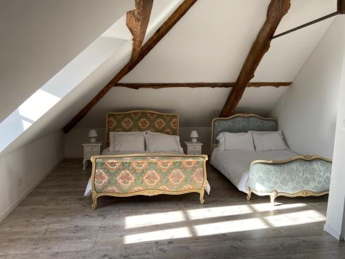 2 łóżka w pokoju na poddaszu z belkami stropowymi w obiekcie L'Enquenoiulle Basse w mieście Verdun-en-Lauragais