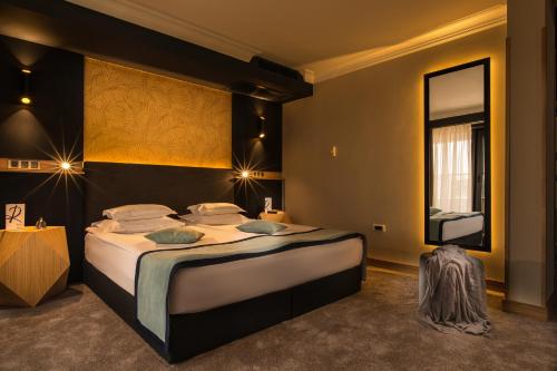 a bedroom with a large bed and a large mirror at Rosslyn Thracia Hotel Sofia in Sofia