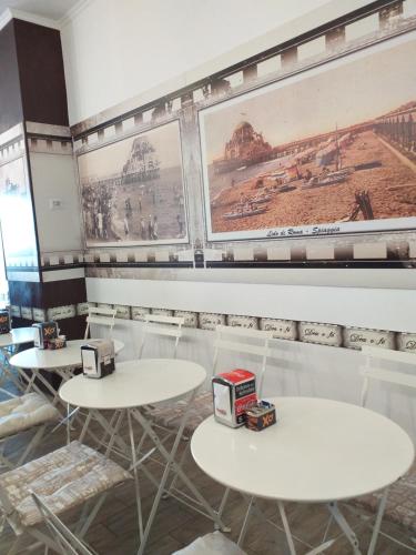 a restaurant with white tables and pictures on the walls at B&B Acquamarina in Lido di Ostia