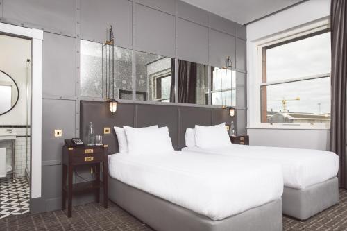 a bedroom with a large white bed and a window at Titanic Hotel Belfast in Belfast