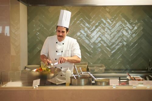 a chef standing in a kitchen preparing food at Sunrise Jade - Adults Only in Protaras