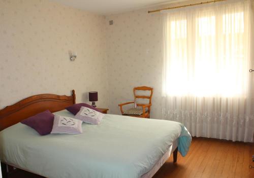 um quarto com uma cama, uma janela e uma cadeira em Chambre au bruand em Saint-Porchaire