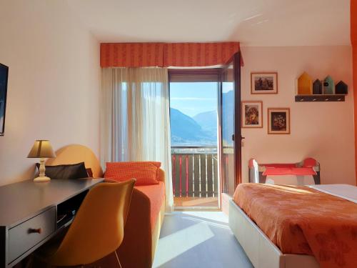 a bedroom with a bed and a desk and a balcony at Family Hotel Primavera in Levico Terme