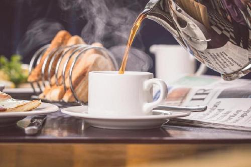 a cup of coffee on a table with a newspaper at Titanic Hotel Belfast in Belfast