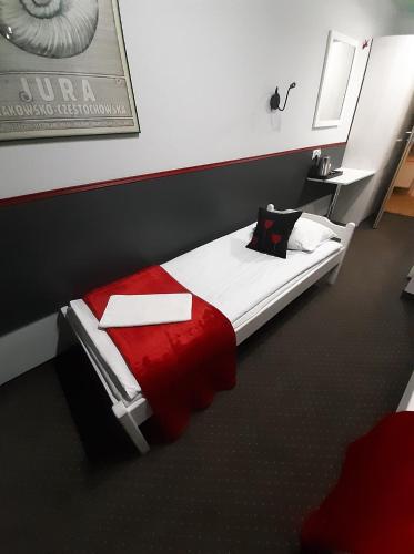 a bedroom with a bed with a red blanket at Pensjonat Maja in Nowy Sącz