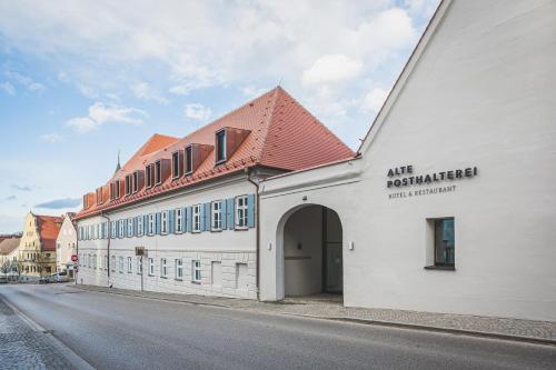a white building with a red roof on a street at Hotel & Restaurant Posthalterei in Zusmarshausen