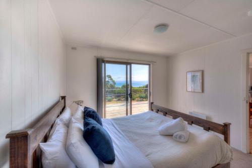 a bedroom with a bed with a large window at Waders in Coles Bay