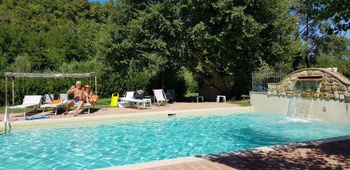 a man sitting in a chair next to a swimming pool at Borgo da Vinci in Volterra