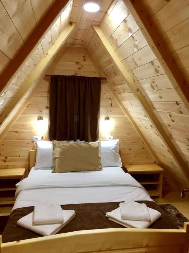 a bed in the attic of a log cabin at B&B Izvor in Žabljak