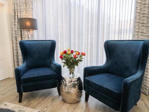 two blue chairs and a vase of flowers in a room at Eagle Fern in Bamburgh