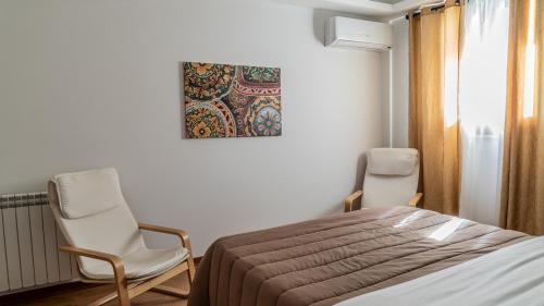 a bedroom with two chairs and a bed and a painting at Residence Rapisardi by RECEPTIO in Catania